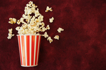 Popcorn in a paper cup and popcorn scattered on a red background with space for text and image. Flat Lay, Top View. Background, pattern, card. Cinema concept.