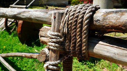 fence of wooden poles tied by a thick rope seen from a side perspective. selective focus