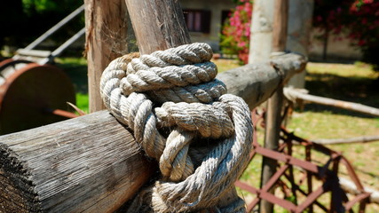 Fototapeta na wymiar fence of wooden poles tied by a thick rope seen from a side perspective. selective focus