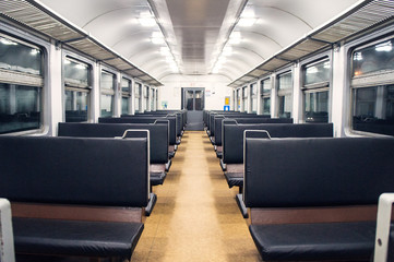 Interior of an empty train carriage with metal shelves and leather seats.