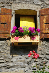 View of a window with shutters with colorful flower windowboxes