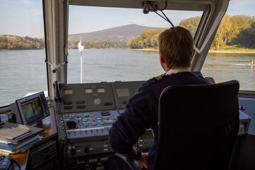 Bratislava, Slovakia. 2019/10/13. A helmsman pilots a ship on the river Danube. - obrazy, fototapety, plakaty