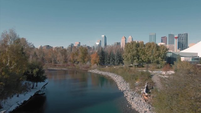 Aerial: Flying over the Elbow river  for an establishing shot of the Calgary city skyline. Calgary, Alberta, Canada. 