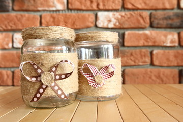 DIY Home decor - decorated jars with natural string with a bow on the background of a brick wall
