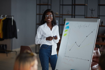Personable african woman in eyeglasses, wearing white shirt and jeans, using diagrams, motivated...