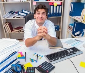 Businessman working in the office with piles of books and papers