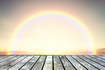 Wood table top on rainbow with sunset sky background