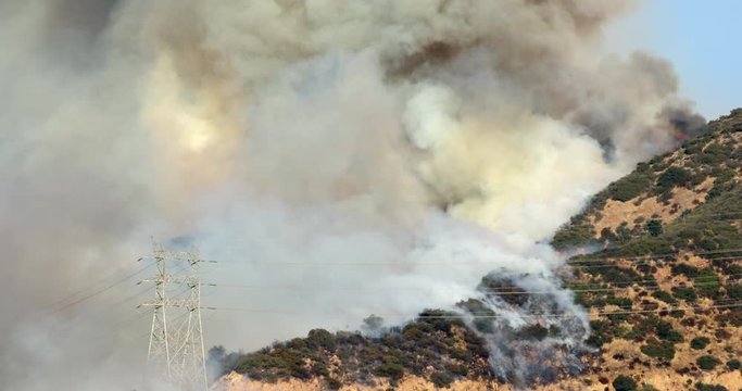 Simi fire. Thick smoke over the California hills completely cover the sky over the burning area. Massive devastating disaster. View over the blazing forest and smoky sky. 4K