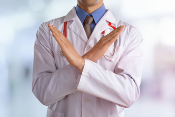 Young doctor with a stethoscope shows stop sign with his hands