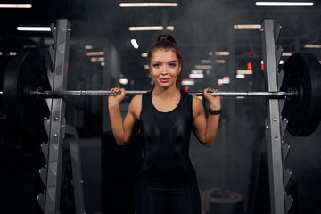 Close view of female athlete dressed, dressed in black stylish sports clothes, holding metal bar on...