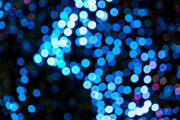 Illuminated Abstract round bright blue  bokeh on dark background. Colourful glitter bokeh from out of focus view of decoration bulbs.