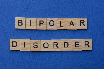 bipolar disorder made from brown wooden letters lies on a blue table