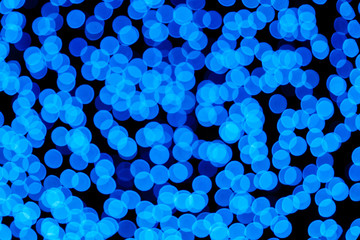 Illuminated Abstract round bright blue  bokeh on dark background. Colourful glitter bokeh from out of focus view of decoration bulbs.