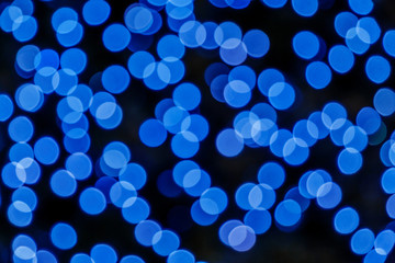 Illuminated Abstract round deep blue bokeh on dark background. Colourful glitter bokeh from out of focus view of decoration bulbs.