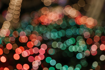 Illuminated abstract round red, orange, green and gold bokeh on dark background. Colourful glitter bokeh from out of focus view of decoration bulbs.