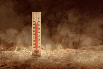 Thermometer with high temperature on the desert with a dusty background