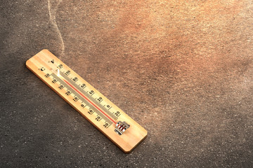 Thermometer with high temperature on the street with glowing sun background