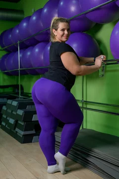 A fat woman is engaged in aerobics and trying to lose weight. An obese girl  is relaxing in the gym with fitness balls. Stock Photo