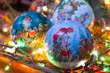 Three balls gift on Christmas tree / New Years holidays gift postcard with holiday lights (horizontal, closeup)