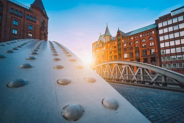 Perspektive der eisernen Bogenbrücken in historischen Lagerhäusern im Stadtteil Speicherstad in Hamburg, Deutschland. Von hinten beleuchtete Sonnenlichtfackeln © Igor Tichonow