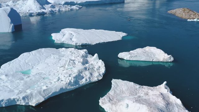Iceberg and ice from glacier in arctic nature landscape on Greenland. Aerial video drone footage of icebergs in Ilulissat icefjord. 4K Aerial Drone shot. Affected by climate change and global warming.