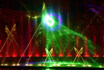 Colorful water fountains. Beautiful laser and fountain show. Large multi colored decorative dancing water jet led light fountain show at night. Dark background.