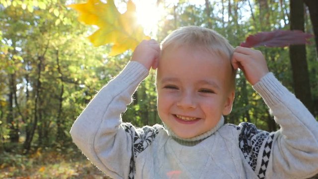 Hilarious giggling kid having fun in autumn forest, entertaining with leaves