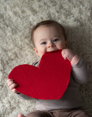Cute baby boy holding red heart