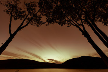 Silhouetted trees framing sunset over a lake in National Park