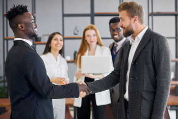 African and caucasian business partners shaking hands each other. Successful deal of business people