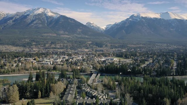 Aerial flying over the town of Canmore and Bow River near Banff. The town is surrounded by the Canadian Rocky Mountains. Alberta, Canada. 