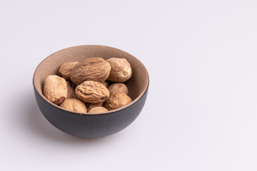 Nutmeg spice in a ceramic bowl isolated on white background, soft light, studio shot, copy space
