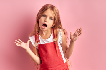 Little caucasian girl expressing fright, fear at camera. isolated pink background
