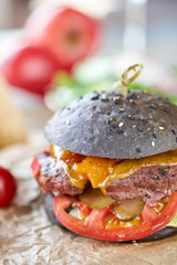 Closeup cheeseburger with lettuce, tomato, fries, and melted cheese. The table in the restaurant. Unhealthy food.