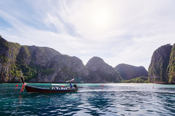 Travel by Thailand. Beautiful tropical lanscape with traditional lontail boat sailing the sea with famous Maya Bay on the background.
