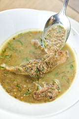 A bowl of homemade chili lentil soup with meat on wooden table. Restaurant menu