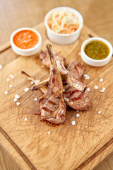 Rack of lamb , grilled meat with bone with Pickled cabbage and two sauces. Serving on a wooden Board. Barbecue restaurant menu, a series of photos of different meats.