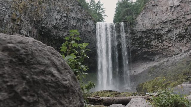 Tamawanas Falls Waterfall Basalt Cliff Zoom In Reveal Low Angle From Behind Rock Slow Motion Pacific Northwest Oregon Mount Hood Territory