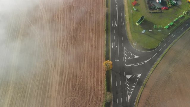 A road through a rural agricultural area in Luxembourg, top down shot of a morning with fog.