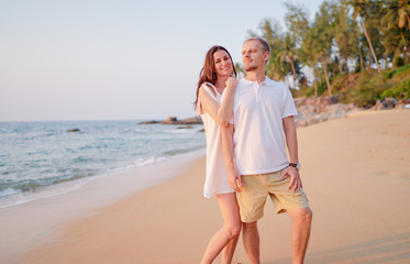Love and romance. Honeymoon on the sea shore. Beautiful loving couple in white cloth embracing on the beach.
