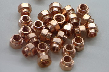 New copper metal nuts on white background close up