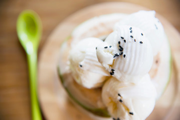 Fototapeta na wymiar Coconut ice cream serving in fresh coconut shell on wooden table - tasty famous sweet dessert