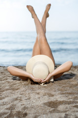 Closeup of young woman in swimsuit and hat  taking sunbath