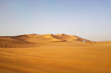 Fototapeta na wymiar Landscape of desert in Dubai, sand dunes which lack of water and vegetation in hot weather under the blue sky in daylight, and rapid temperature change between day and night when darkness revisited.