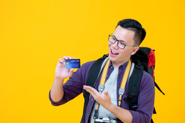 Smiling excited Asian tourist backpacker showing credit card in hand