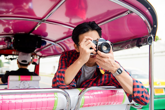 Tourist taking photo while traveling on Tuk Tuk taxi in Bangkok Thailand