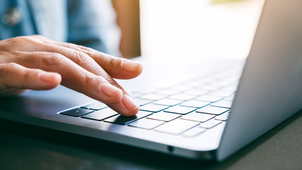 Closeup image of a woman's finger pressing on the enter button of laptop computer on the table