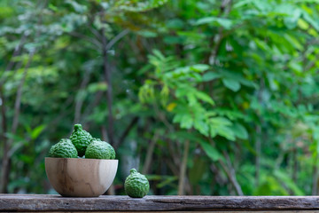 Fresh organic bergamot fruits on wooden table with blur green garden background - obrazy, fototapety, plakaty
