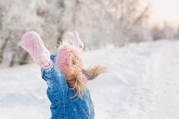 Little girl throws up snow and plays with it in woods in winter