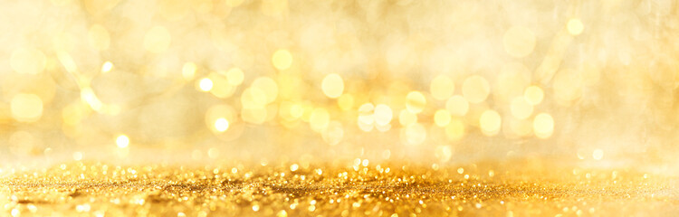 Abstract bokeh of glowing yellow lights and sparkling gold glitter background or wallpaper